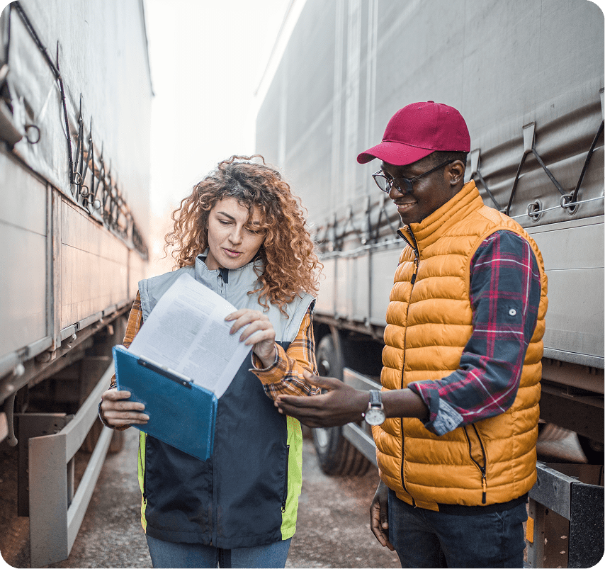 Two people reviewing documents between trucks.