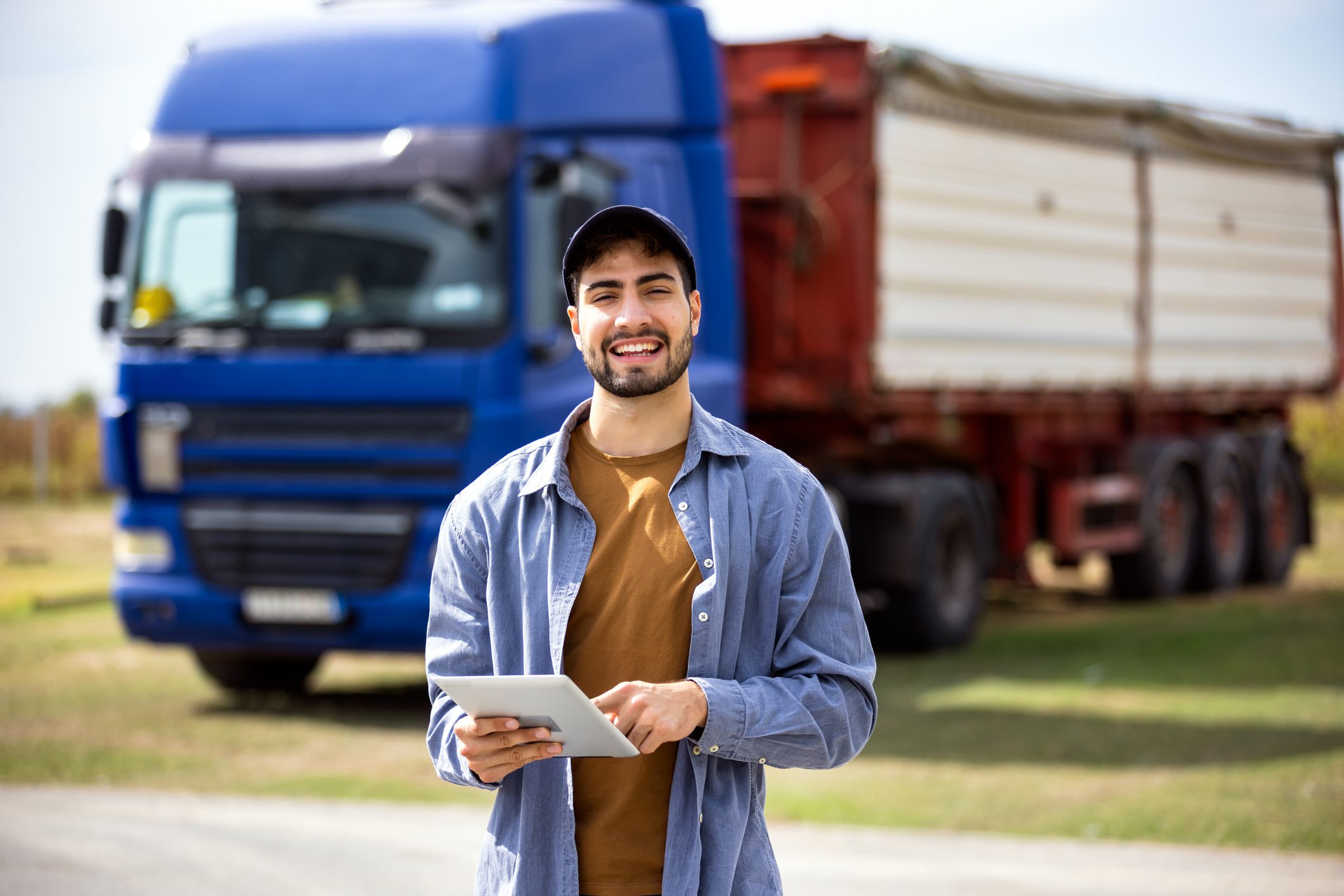 Truck driver holds tablet while standing in front of truck, concept of modern logistics, transport, digital technology, professional driver, cargo service.